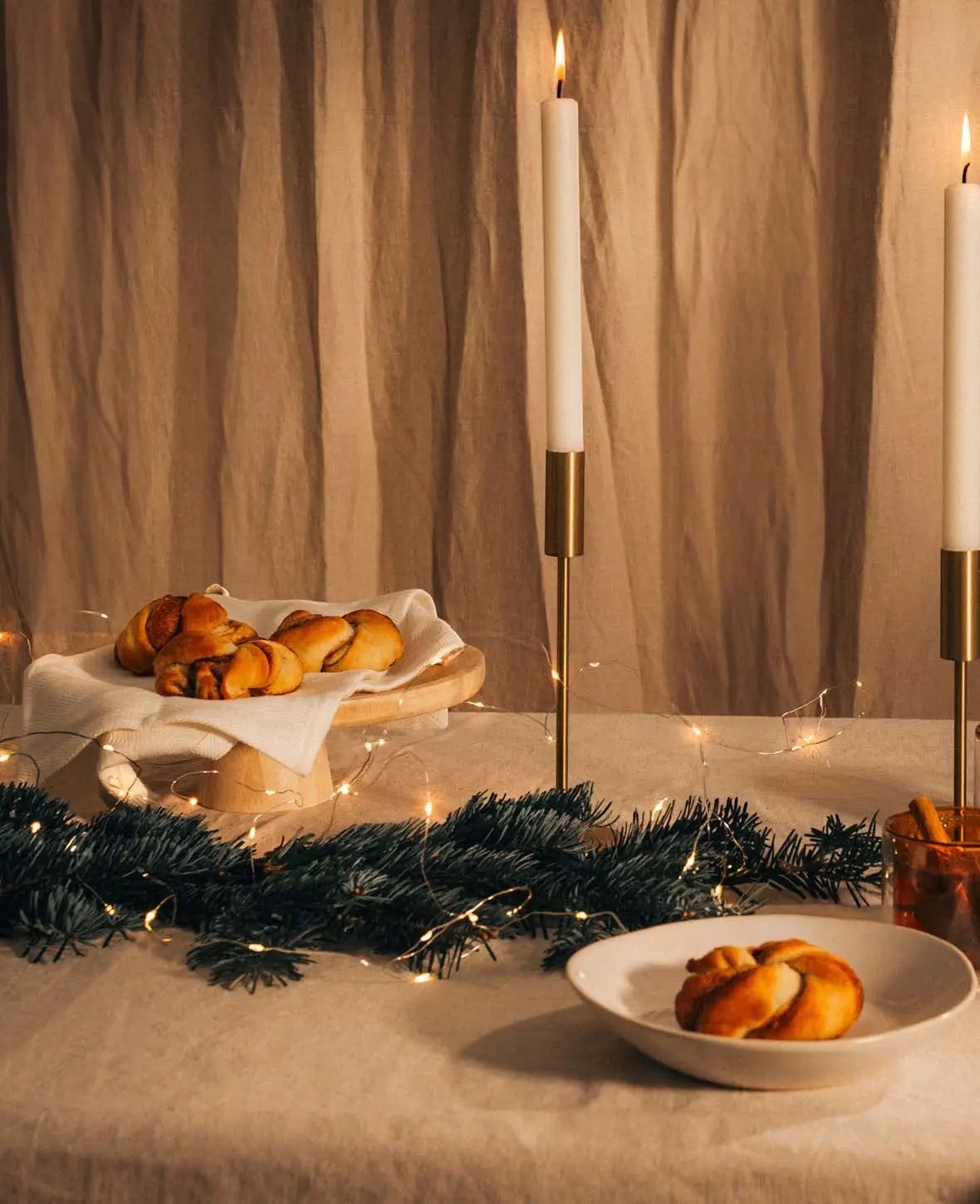Esmée Kerzenständer aus glänzendem Messing Gold für Stabkerzen, dekoriert mit Tannenzweigen und Gebäck auf einem Tisch