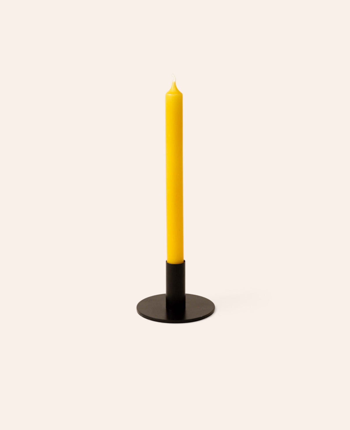 Esmée senfgelbe Stabkerze in einem minimalistischen schwarzen Kerzenhalter vor hellem Hintergrund