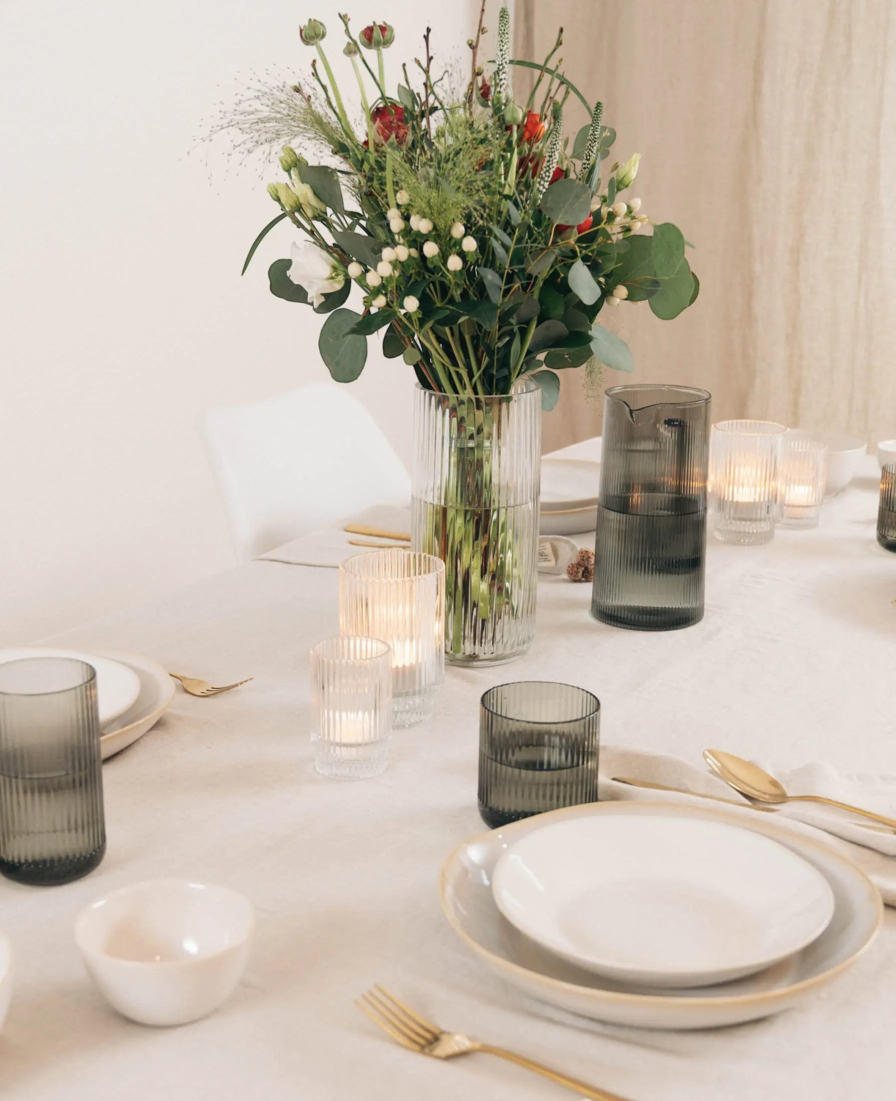 Esmée Teelichtglas mit Rillen auf einem festlich gedeckten Tisch mit Blumenstrauß und Kerzenschein