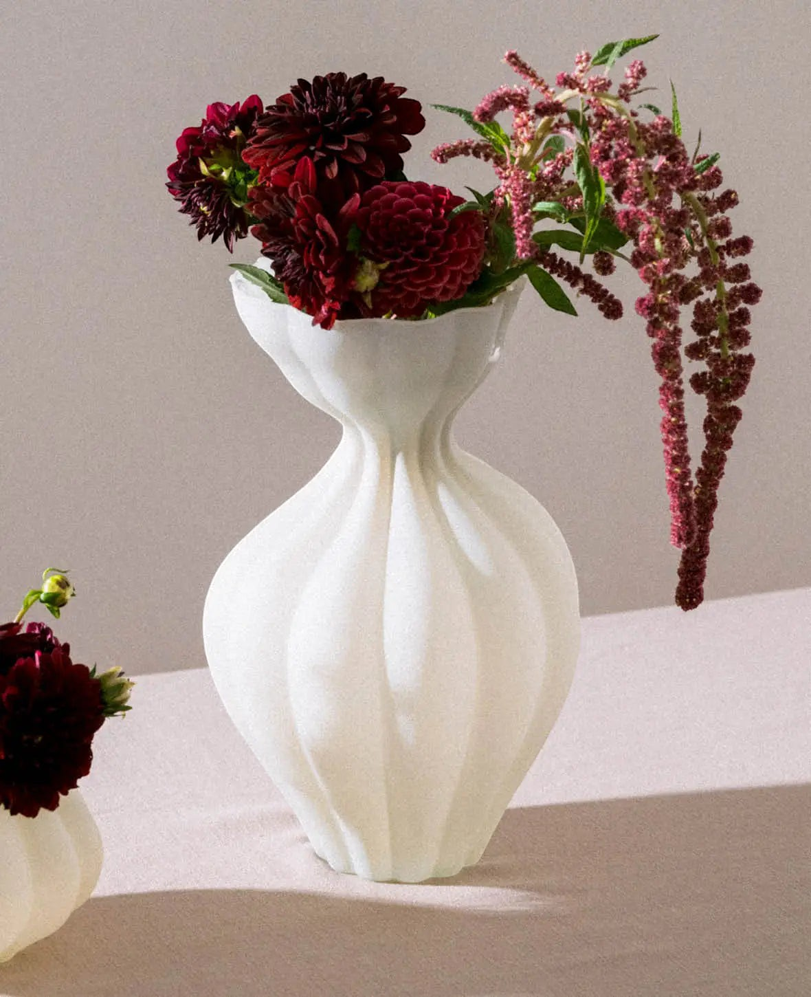 Esmée Vase in organischer Form aus beigem Glas mit Blumenstrauß auf einem Tisch