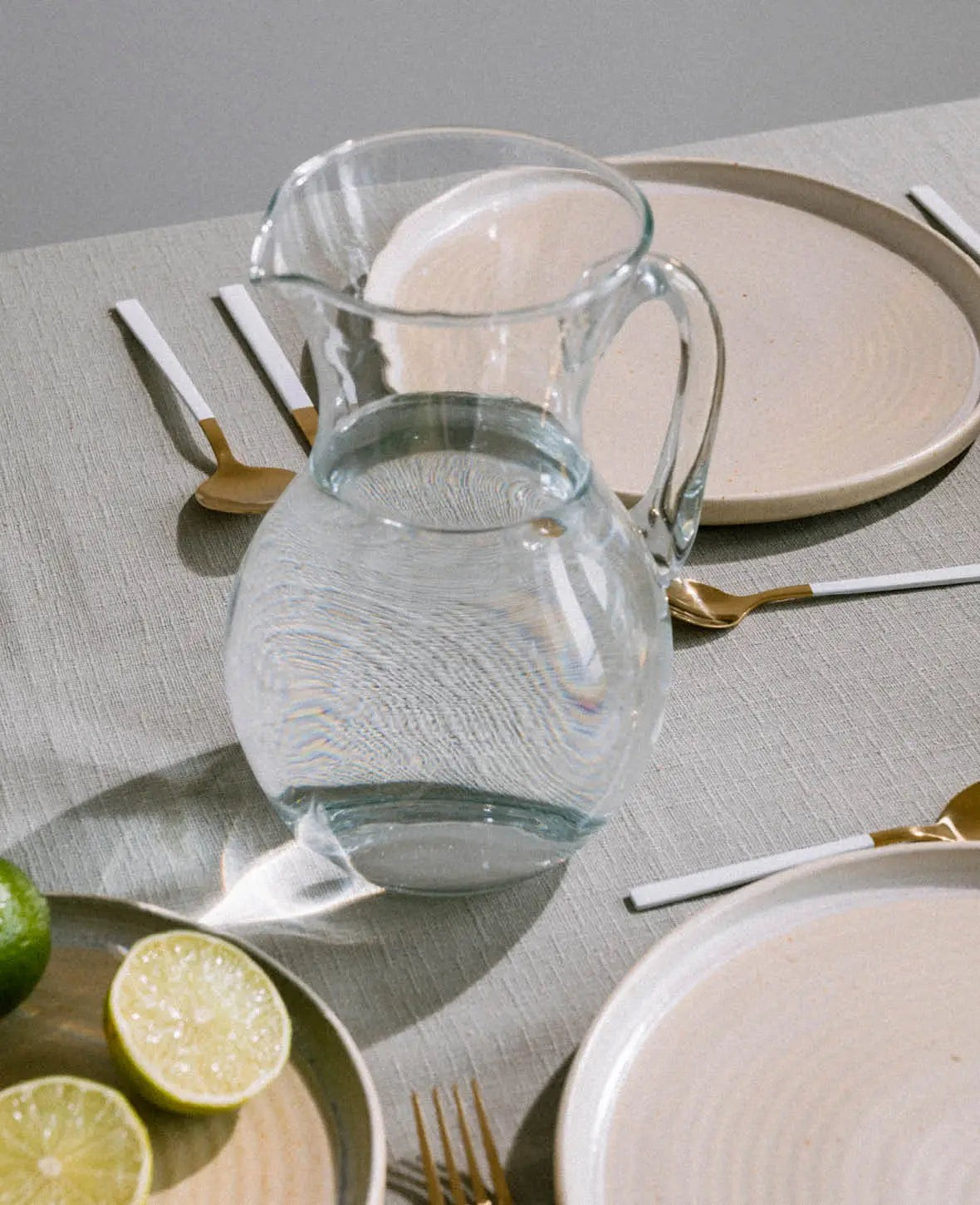 Esmée Glaskrug aus klarem Glas mit 1,5 Liter Fassungsvermögen auf einem gedeckten Tisch mit Limetten und Besteck