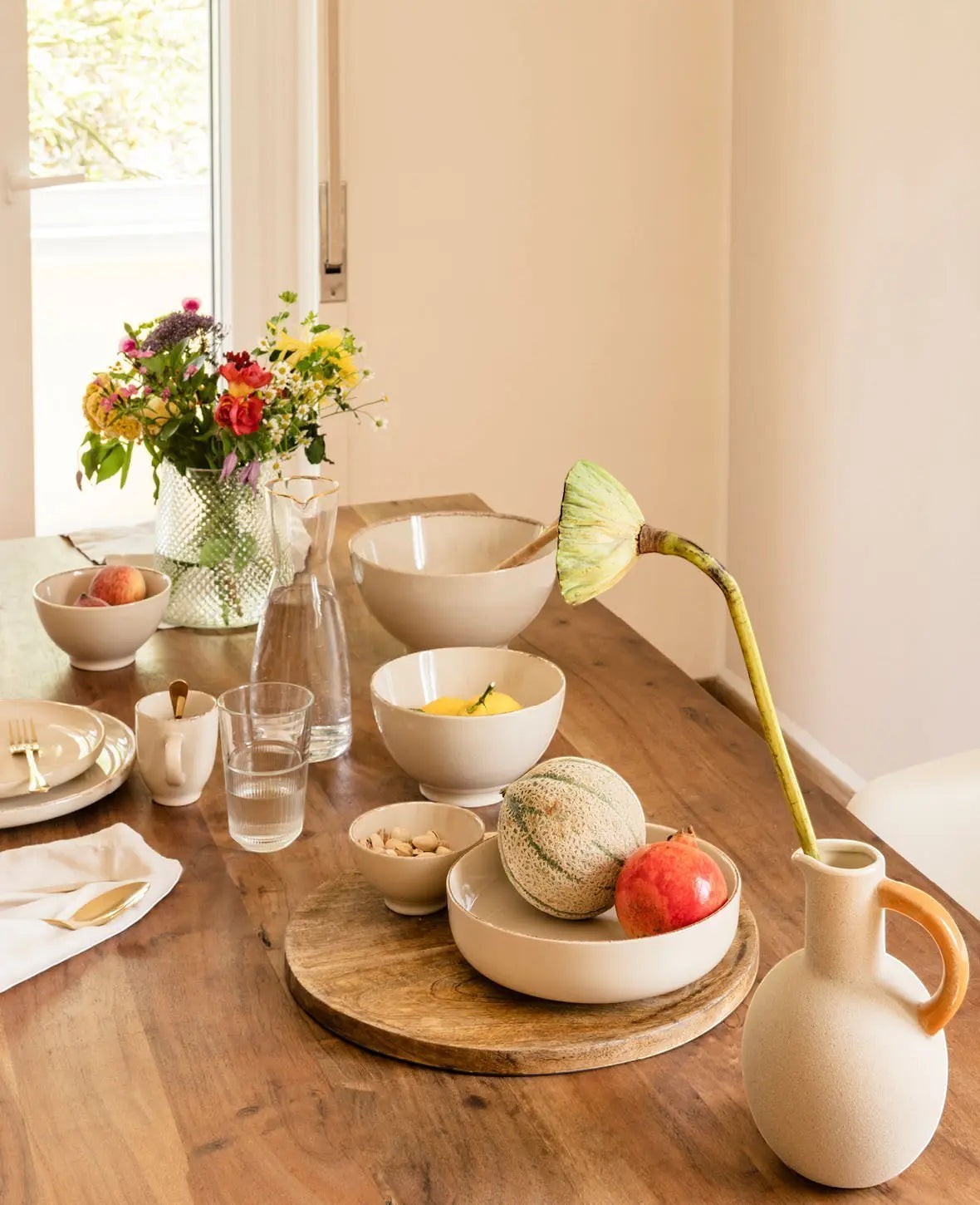 Esmée Keramikschale in Beige auf einem gedeckten Holztisch mit Obst und Blumen in einem hellen Wohnraum