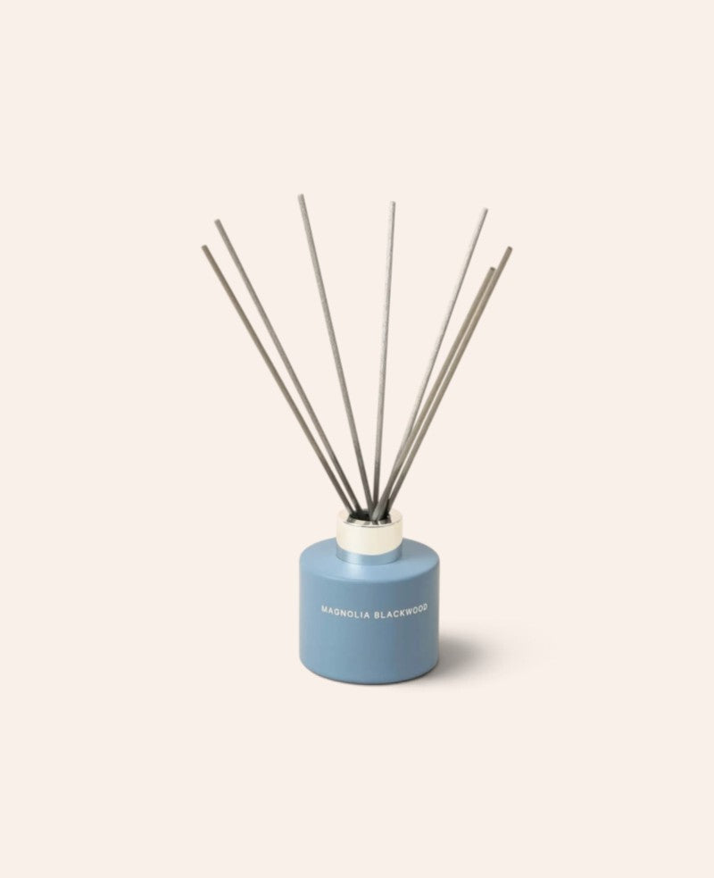 Esmée Duft Diffuser Magnolia Blackwood in einem matten blauen Glasbehälter mit sieben grauen Holzfaser-Stäbchen