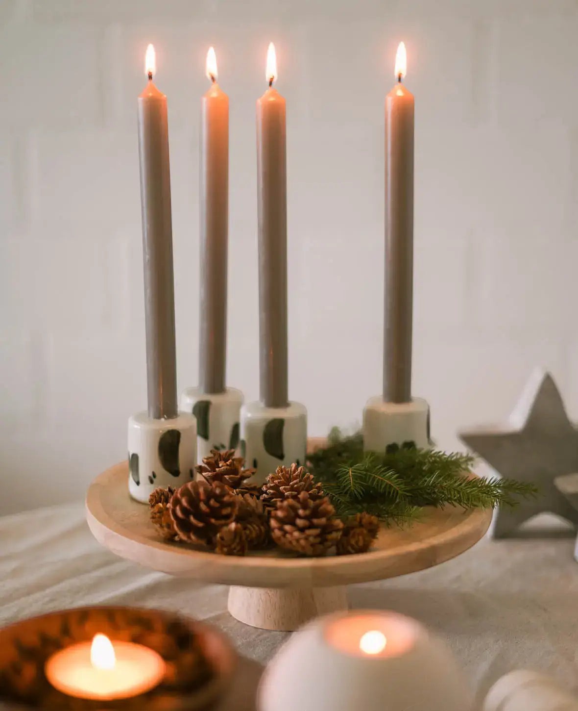 Esmée Keramik Kerzenständer in Weiss mit schwarzen Pinseleffekten auf einem Holztablett mit Tannenzweigen und Zapfen
