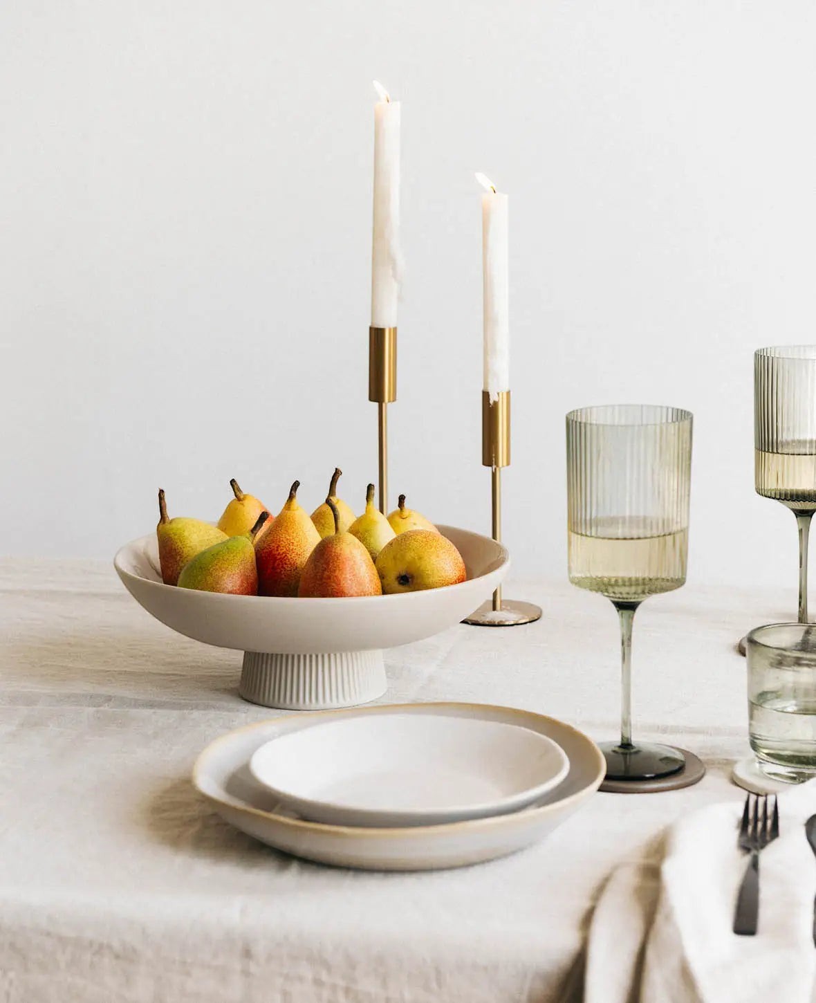 Esmée Kerzenständer aus glänzendem Messing Gold für Stabkerzen auf einem elegant gedeckten Esstisch mit Obstschale