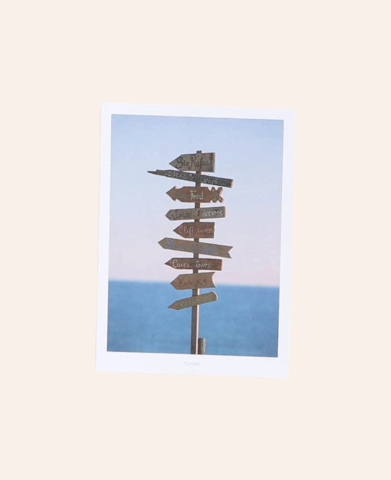 Esmée Postkarte im A6 Format mit einem hölzernen Wegweiser vor blauem Meer auf mattem Naturpapier