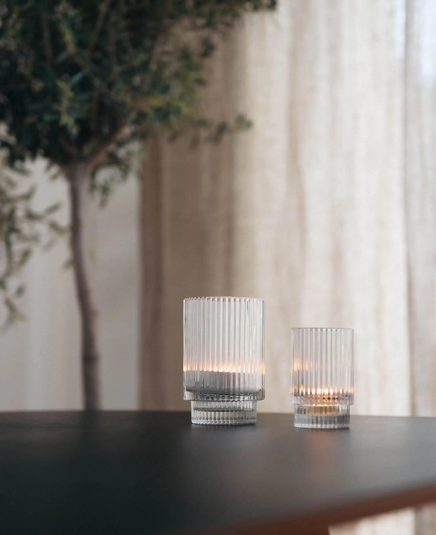 Esmée Teelichtglas mit Rillen aus klarem Glas auf einem dunklen Tisch für eine gemütliche Lichtstimmung