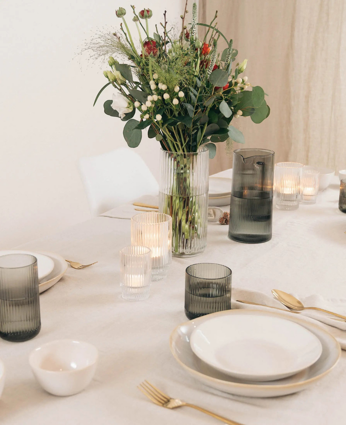 Esmée Teelichtglas mit Rillen auf einem festlich gedeckten Tisch mit Blumenstrauß und Kerzenschein