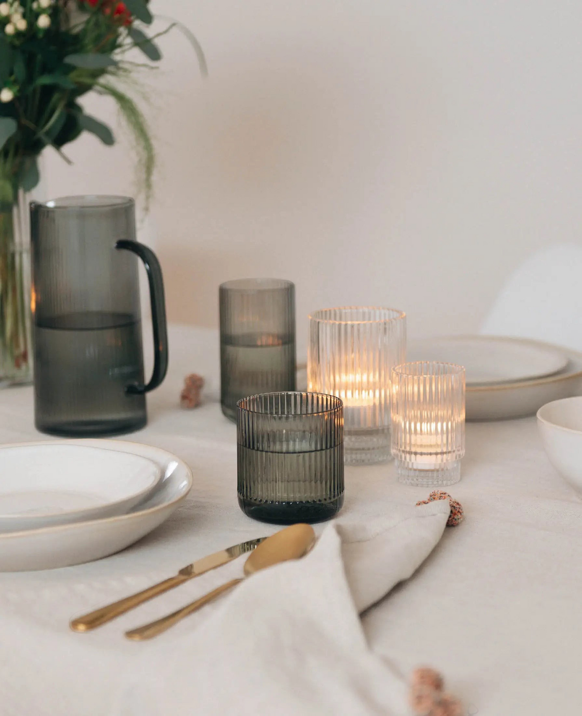 Esmée Teelichtglas mit Rillen auf einem gedeckten Tisch mit Kerzenschein und passender Glaskaraffe